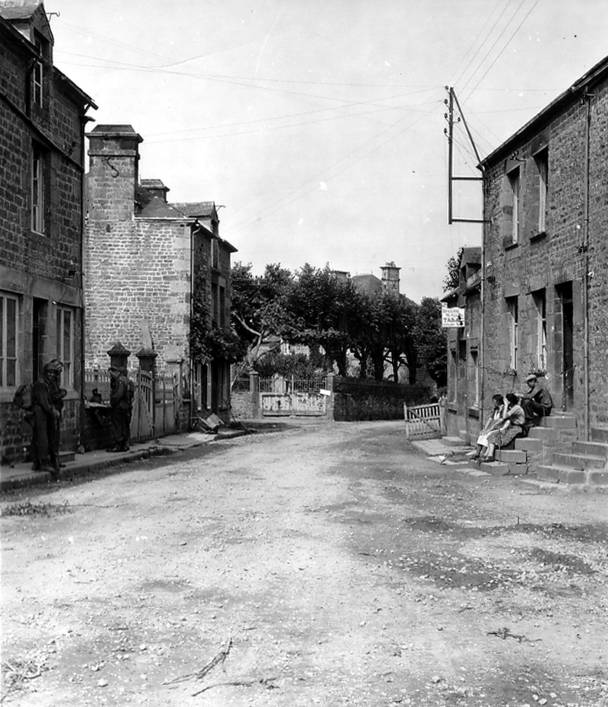 Des civils français assis sur le perron d'une maison à Beauvain.